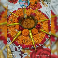 a bowl filled with yellow flowers on top of a red and white table cloth next to gold spoons