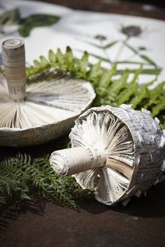 two paper umbrellas sitting on top of a table next to green leaves and plants