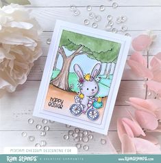 a card with an image of a bunny on a bike and flowers in the background