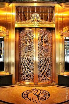 the entrance to an elevator in a building with ornate doors and chandeliers on either side