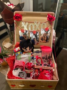 an open suitcase filled with valentine's day items and gifts on a table next to a vase