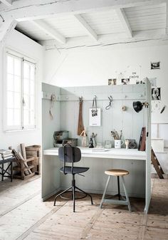 a room with white walls and wooden flooring, two stools on the far side