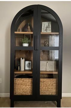 a black bookcase with wicker baskets and books on it's front doors