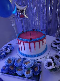 a birthday cake with blue and red icing on it next to other desserts