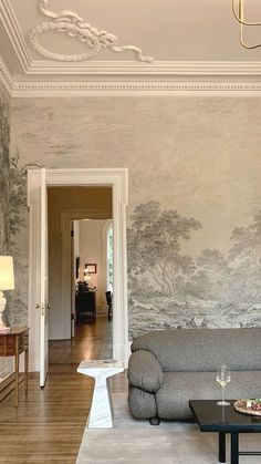 a living room filled with furniture and walls covered in wallpapered trees on either side of the couch