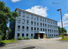 an empty parking lot in front of a large gray building with lots of windows on it