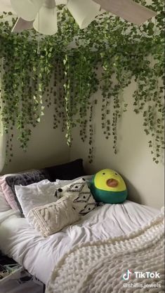 a bed with lots of pillows and plants hanging from the ceiling