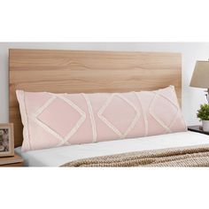 a bed with pink pillows on it and a wooden headboard in the background,