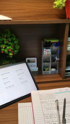 an open notebook and pen sitting on top of a desk next to a computer monitor