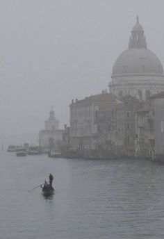 a person in a boat on a body of water with buildings and towers behind them