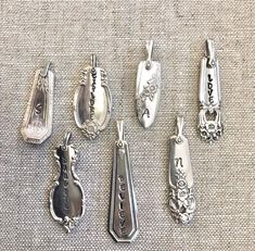 six antique silver spoons are sitting on a tablecloth with the word love spelled below them