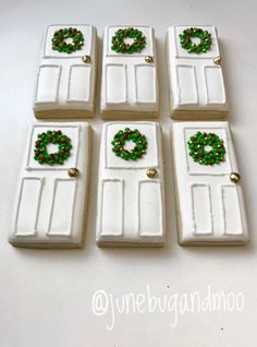 six white doors decorated with green and red beaded wreaths are on the table