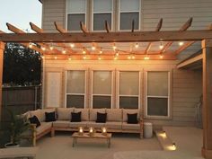 an outdoor living area with couches and lights on the pergolated patio roof