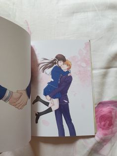 an open book with a drawing of two people holding each other's arms and kissing