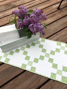 a vase filled with purple flowers sitting on top of a wooden table next to a napkin