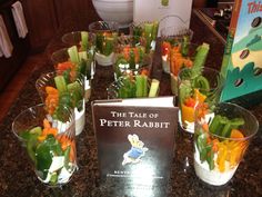 a table topped with glasses filled with veggies next to a book and cookbook