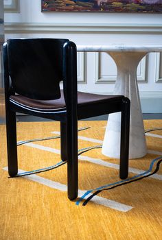 a black chair sitting on top of a wooden floor next to a white pedestal table