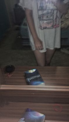 a person standing in front of a mirror with a book on the floor next to it