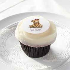 a cupcake with frosting and a teddy bear sticker sitting on a plate