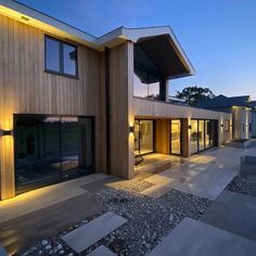 a modern house is lit up at night with lights on the windows and patio area