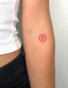 a woman's arm with a tattoo on it that has a pink circle in the middle