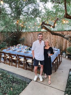 a man and woman standing next to each other in front of a table covered with blue cloths