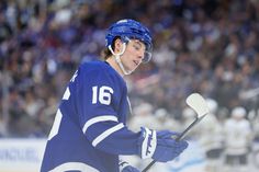 a hockey player with ear buds on his ears and holding a stick in front of an audience