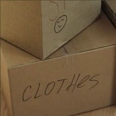 two cardboard boxes with clothes written on them