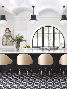 an elegant kitchen with black and white tile flooring, gold accents and modern chairs