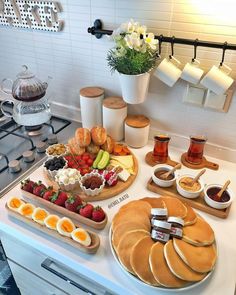 the breakfast is ready to be eaten on the kitchen counter top, including eggs, fruit, and pancakes