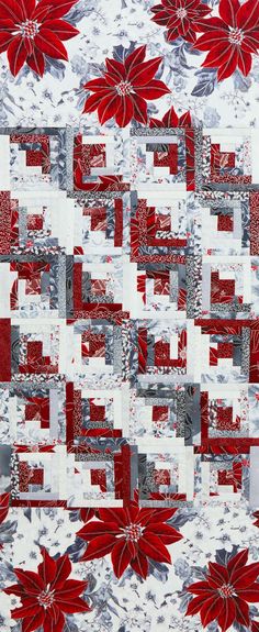 a red and white quilt with poinsettia flowers on the front, along with grey background