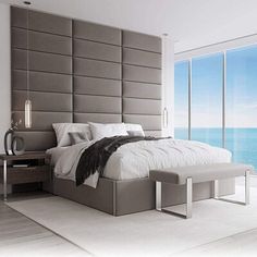 a large bed sitting in the middle of a bedroom next to an ocean side window