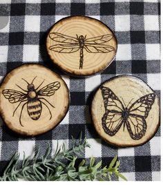 three bees and a bee on wood slices are sitting on a checkered tablecloth