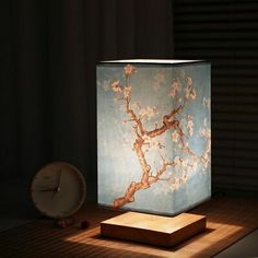 a lamp that is sitting on top of a wooden table with a clock in front of it