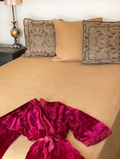 the bed is covered with red sheets and pillows