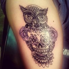 an owl tattoo on the thigh with roses