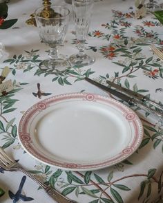 an empty plate is sitting on a floral tablecloth with utensils and silverware