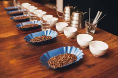 there are many cups and bowls lined up on the table with coffee beans in them