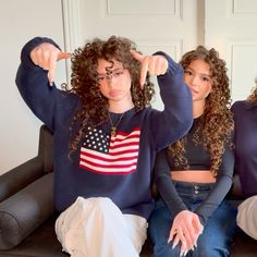 three women sitting on a couch with their arms in the air and pointing at something