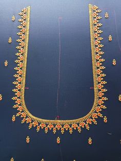 an elaborate gold necklace is displayed on a blue surface with red and yellow beads around it