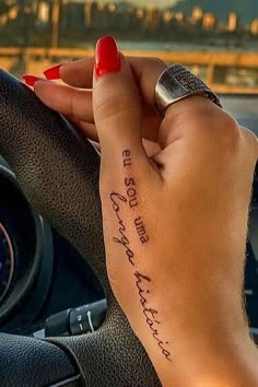 a woman driving a car with her hand on the steering wheel and writing on it