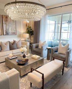 a living room filled with furniture and a chandelier hanging over the top of it