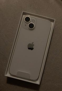 an apple phone in its box on the table with it's camera lens open