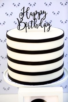 a black and white striped cake with the words happy birthday on top