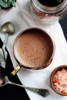 there is a cup of hot chocolate and spoons on the table next to it