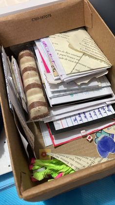 an open cardboard box filled with lots of papers and other items on top of a blue table