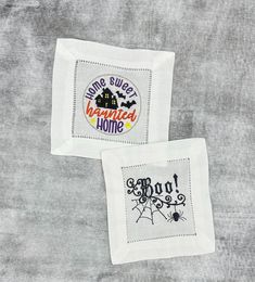 two embroidered napkins sitting on top of a table