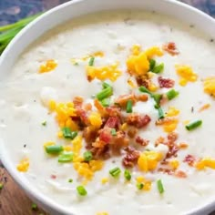 a white bowl filled with soup and topped with bacon, green onions, and cheese