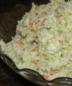 a glass bowl filled with coleslaw and carrots on top of a table