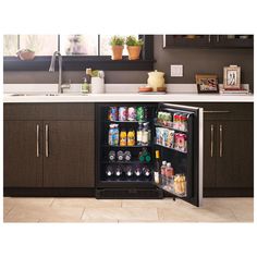 an open refrigerator in a kitchen next to a counter with drinks and condiments